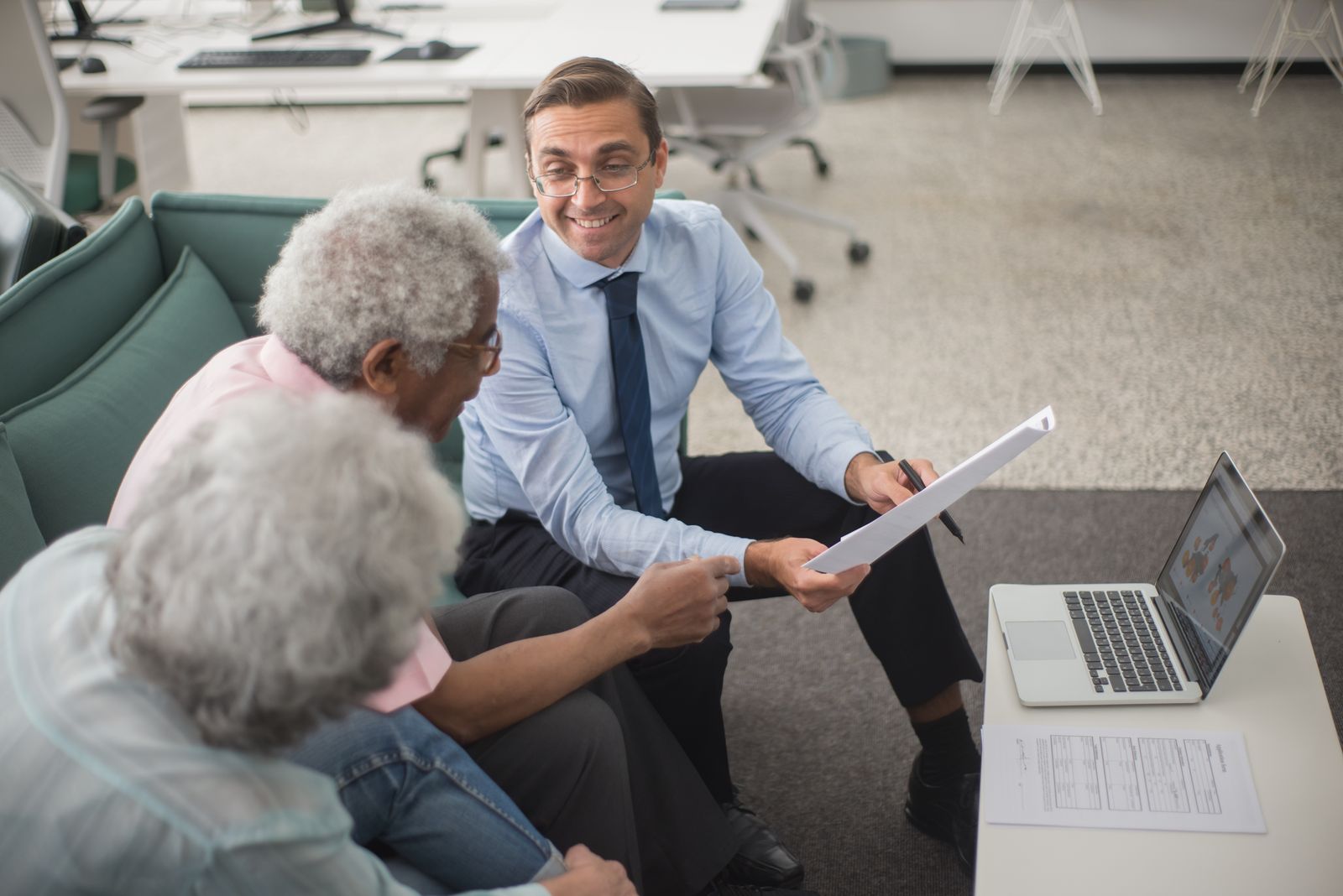 Senior executive reviewing a financial report with staff at a bright office table.