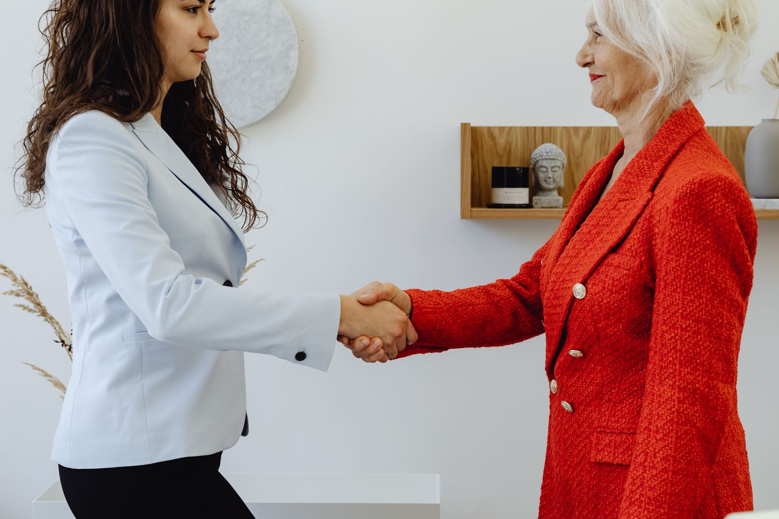 Two professionals meeting warmly across a table during a leadership handoff.