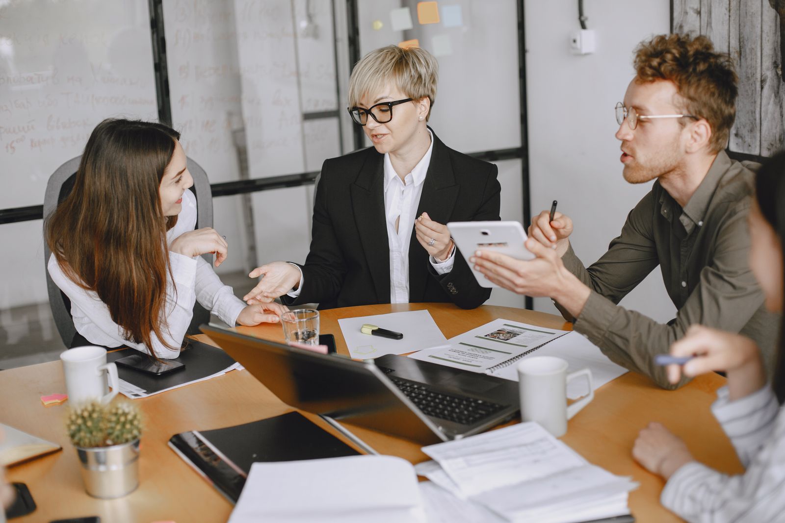 Professional team collaborating over documents and a laptop in a bright meeting room.